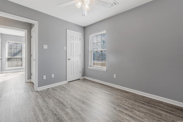 empty room with ceiling fan, light hardwood / wood-style floors, and a textured ceiling