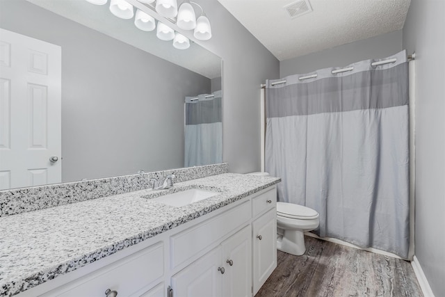 bathroom featuring a shower with shower curtain, vanity, wood-type flooring, a textured ceiling, and toilet