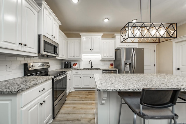 kitchen featuring sink, crown molding, a center island, appliances with stainless steel finishes, and white cabinets