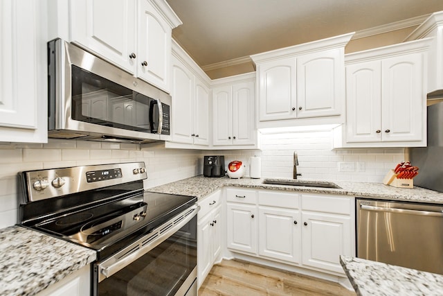 kitchen with sink, white cabinetry, ornamental molding, stainless steel appliances, and light hardwood / wood-style floors