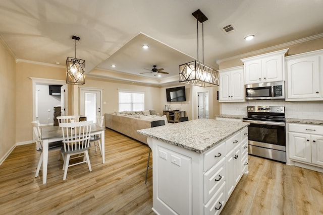 kitchen with white cabinetry, light stone counters, decorative light fixtures, a center island, and appliances with stainless steel finishes