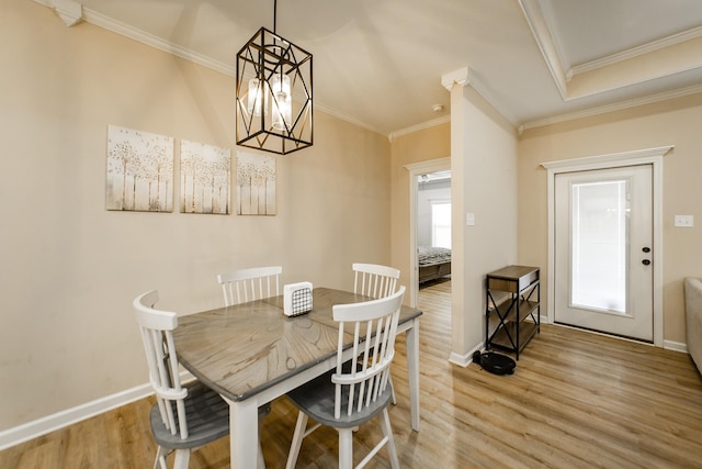 dining area with an inviting chandelier, crown molding, a wealth of natural light, and light hardwood / wood-style floors