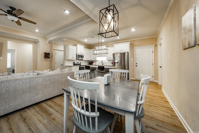 dining room with ceiling fan, ornamental molding, sink, and light wood-type flooring