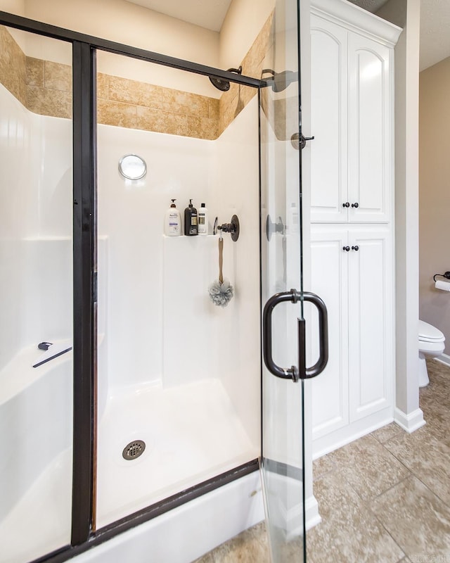 bathroom featuring a shower with shower door and toilet