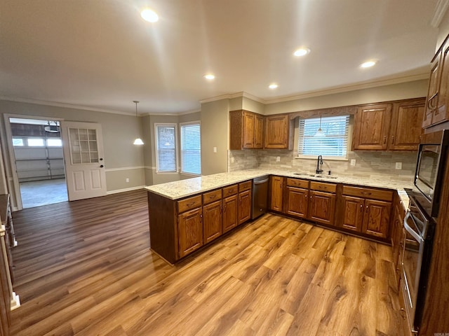 kitchen featuring appliances with stainless steel finishes, sink, hanging light fixtures, light hardwood / wood-style floors, and kitchen peninsula