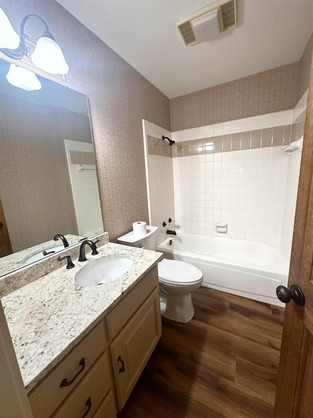 full bathroom with vanity, hardwood / wood-style flooring, toilet, and tiled shower / bath