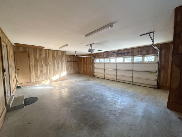 garage featuring a garage door opener and wooden walls