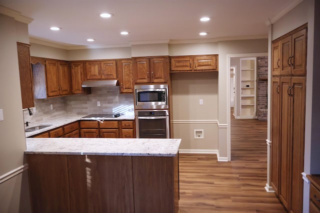 kitchen with appliances with stainless steel finishes, sink, decorative backsplash, crown molding, and light stone countertops