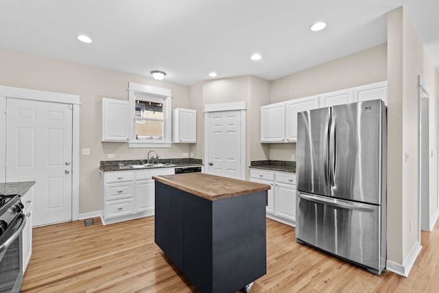 kitchen featuring wood counters, white cabinetry, a kitchen island, stainless steel appliances, and light hardwood / wood-style floors