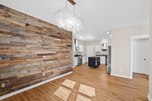 kitchen featuring wood walls, decorative light fixtures, a center island, appliances with stainless steel finishes, and white cabinets