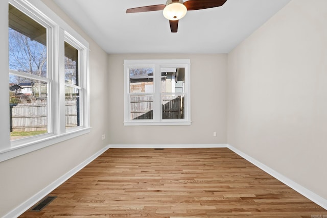 empty room featuring ceiling fan, a healthy amount of sunlight, and light hardwood / wood-style flooring