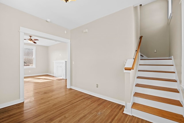 staircase with hardwood / wood-style flooring and ceiling fan