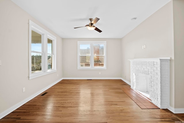 empty room with ceiling fan, wood-type flooring, and a fireplace