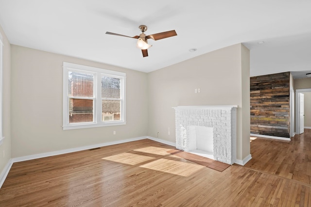 unfurnished living room featuring ceiling fan, a fireplace, and wood-type flooring