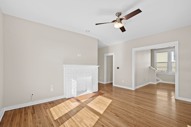 unfurnished living room featuring a brick fireplace, ceiling fan, and light hardwood / wood-style flooring