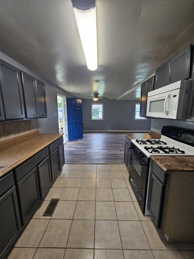 kitchen with black gas range oven, light tile patterned floors, and ceiling fan