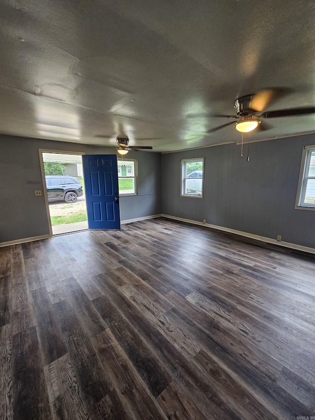 empty room featuring dark wood-type flooring, ceiling fan, and plenty of natural light