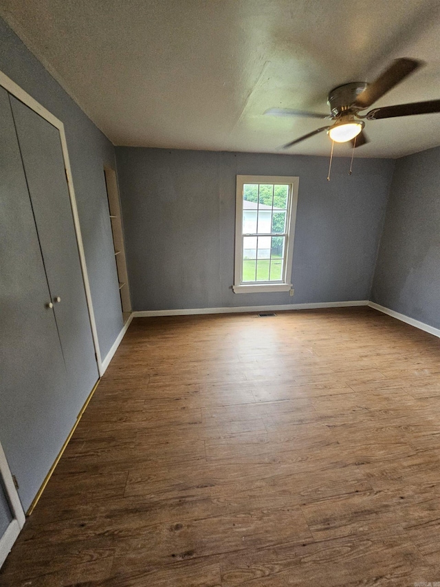 unfurnished bedroom with wood-type flooring, a closet, and ceiling fan