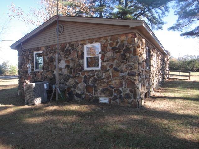 view of property exterior with a yard and central air condition unit