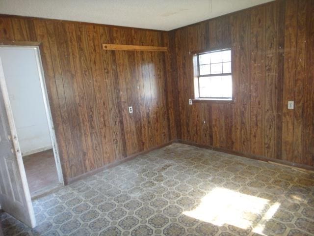 unfurnished room featuring wood walls