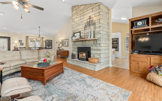 living room with ceiling fan with notable chandelier, vaulted ceiling, and light wood-type flooring