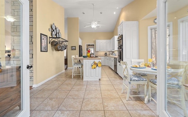 kitchen with light tile patterned floors, a breakfast bar area, appliances with stainless steel finishes, white cabinetry, and a center island