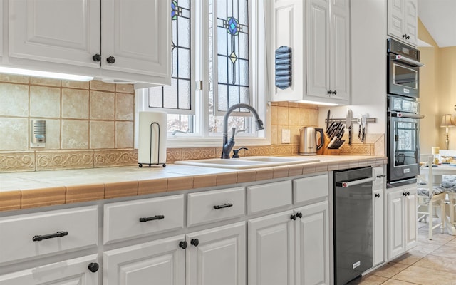 kitchen with sink, tile countertops, white cabinets, and decorative backsplash