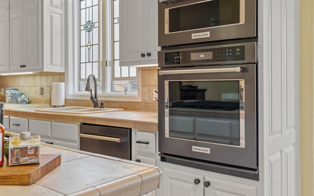 kitchen with white cabinetry, sink, tile countertops, and tasteful backsplash