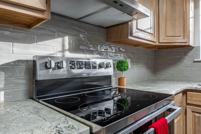 kitchen with stainless steel electric range oven, wall chimney range hood, light stone counters, and decorative backsplash