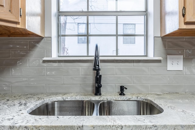 room details with tasteful backsplash, sink, and light stone counters