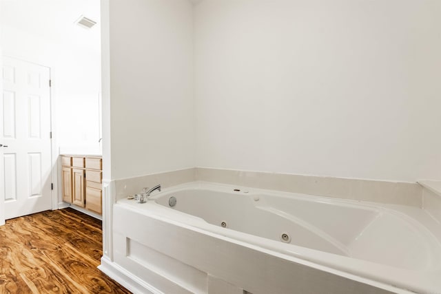 bathroom featuring vanity, hardwood / wood-style floors, and tiled bath