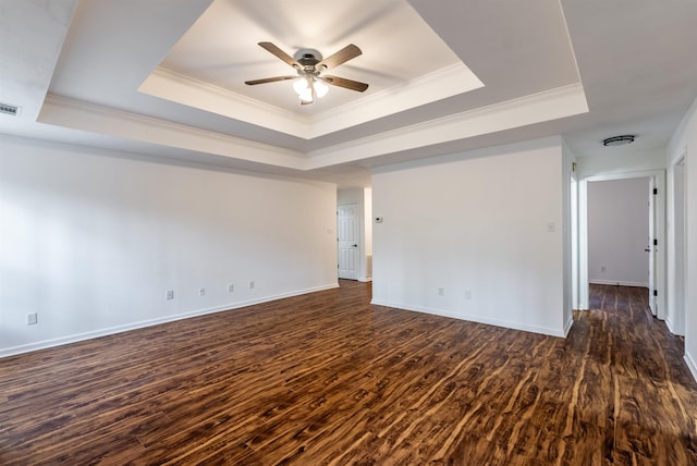 empty room featuring a raised ceiling, ornamental molding, ceiling fan, and dark hardwood / wood-style flooring