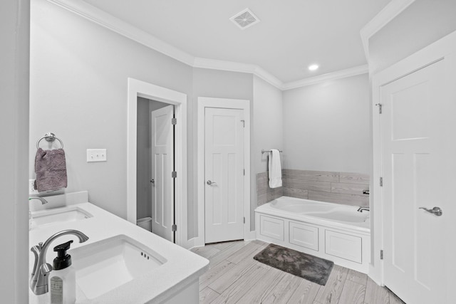 bathroom with hardwood / wood-style flooring, ornamental molding, a bath, and vanity