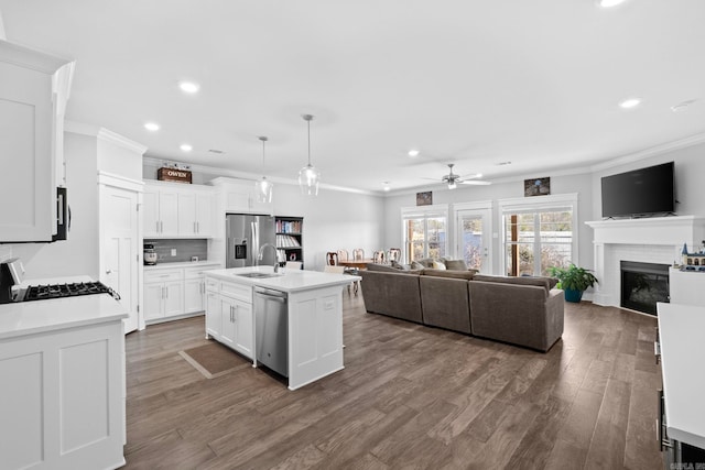 kitchen with white cabinetry, appliances with stainless steel finishes, a center island with sink, and pendant lighting