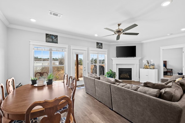 living room featuring crown molding, a brick fireplace, ceiling fan, and light hardwood / wood-style floors