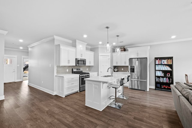 kitchen with sink, white cabinetry, stainless steel appliances, a center island with sink, and decorative light fixtures