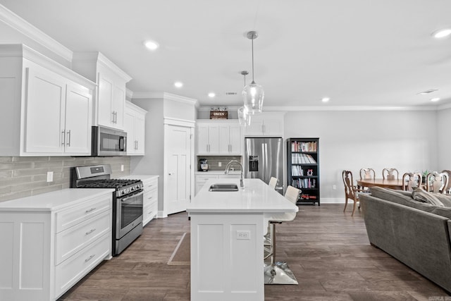 kitchen featuring sink, white cabinetry, a center island with sink, appliances with stainless steel finishes, and pendant lighting