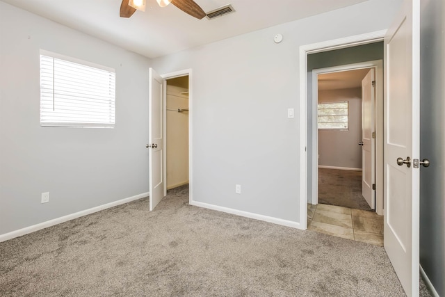 unfurnished bedroom with a spacious closet, light carpet, ceiling fan, and a closet