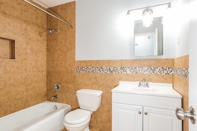 full bathroom with tile walls, vanity, tiled shower / bath, and toilet