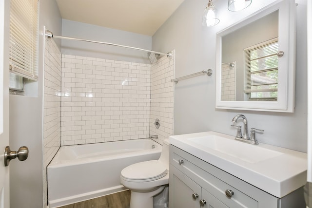 full bathroom with tiled shower / bath combo, vanity, hardwood / wood-style floors, and toilet