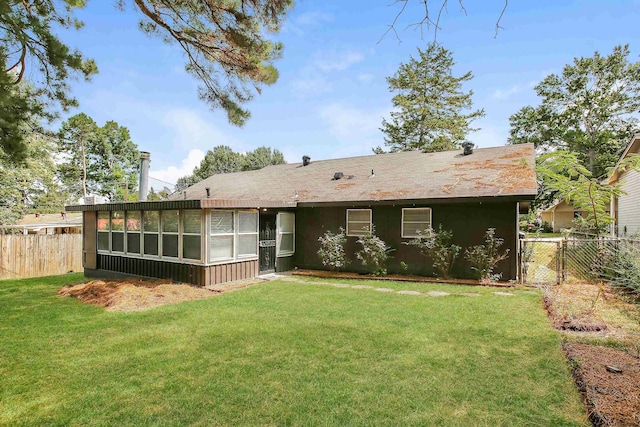 rear view of house with a sunroom and a yard