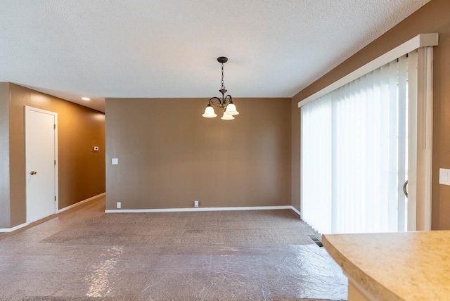 unfurnished dining area featuring an inviting chandelier, carpet floors, and a textured ceiling