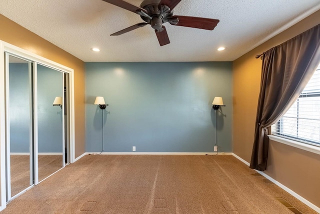 unfurnished bedroom featuring a closet, ceiling fan, carpet floors, and a textured ceiling