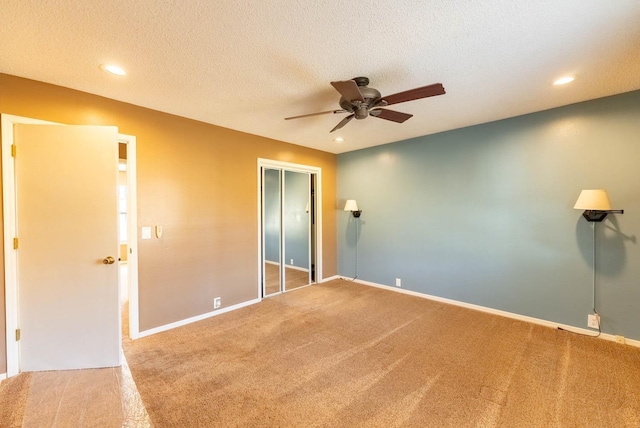 unfurnished bedroom with ceiling fan, a closet, a textured ceiling, and carpet flooring