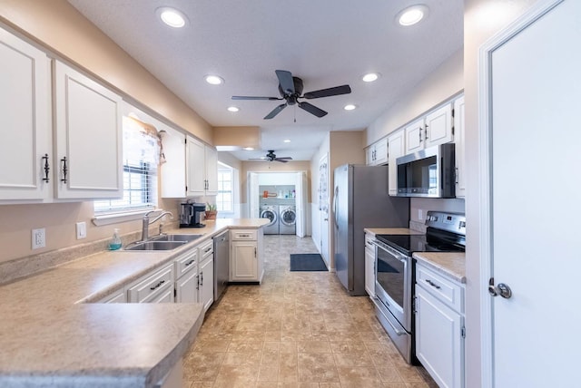 kitchen with white cabinetry, sink, washer and dryer, and appliances with stainless steel finishes