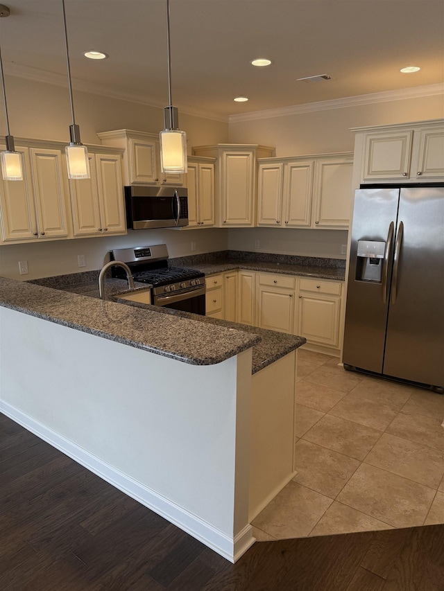 kitchen with decorative light fixtures, stainless steel appliances, kitchen peninsula, and dark stone counters