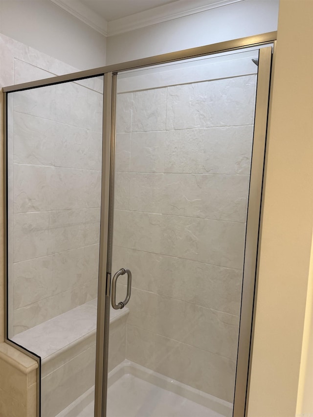 bathroom with a shower with door and ornamental molding