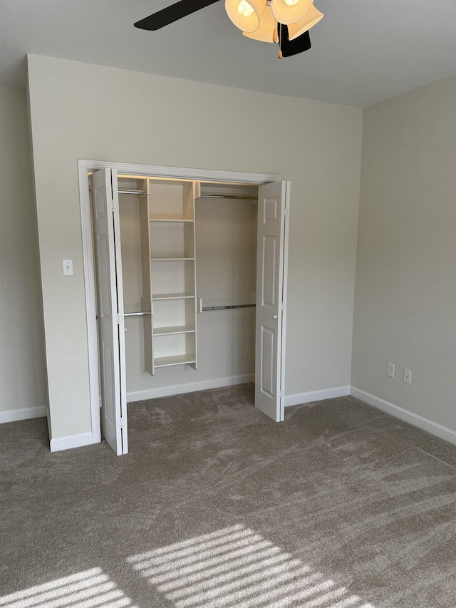 unfurnished bedroom with dark carpet, a closet, and ceiling fan