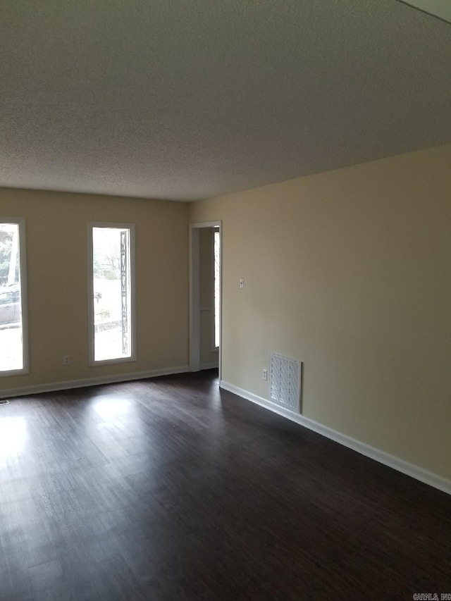 empty room featuring dark hardwood / wood-style floors and a textured ceiling