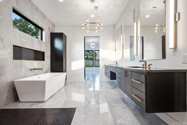 bathroom with vanity, a tub to relax in, a wealth of natural light, and a chandelier